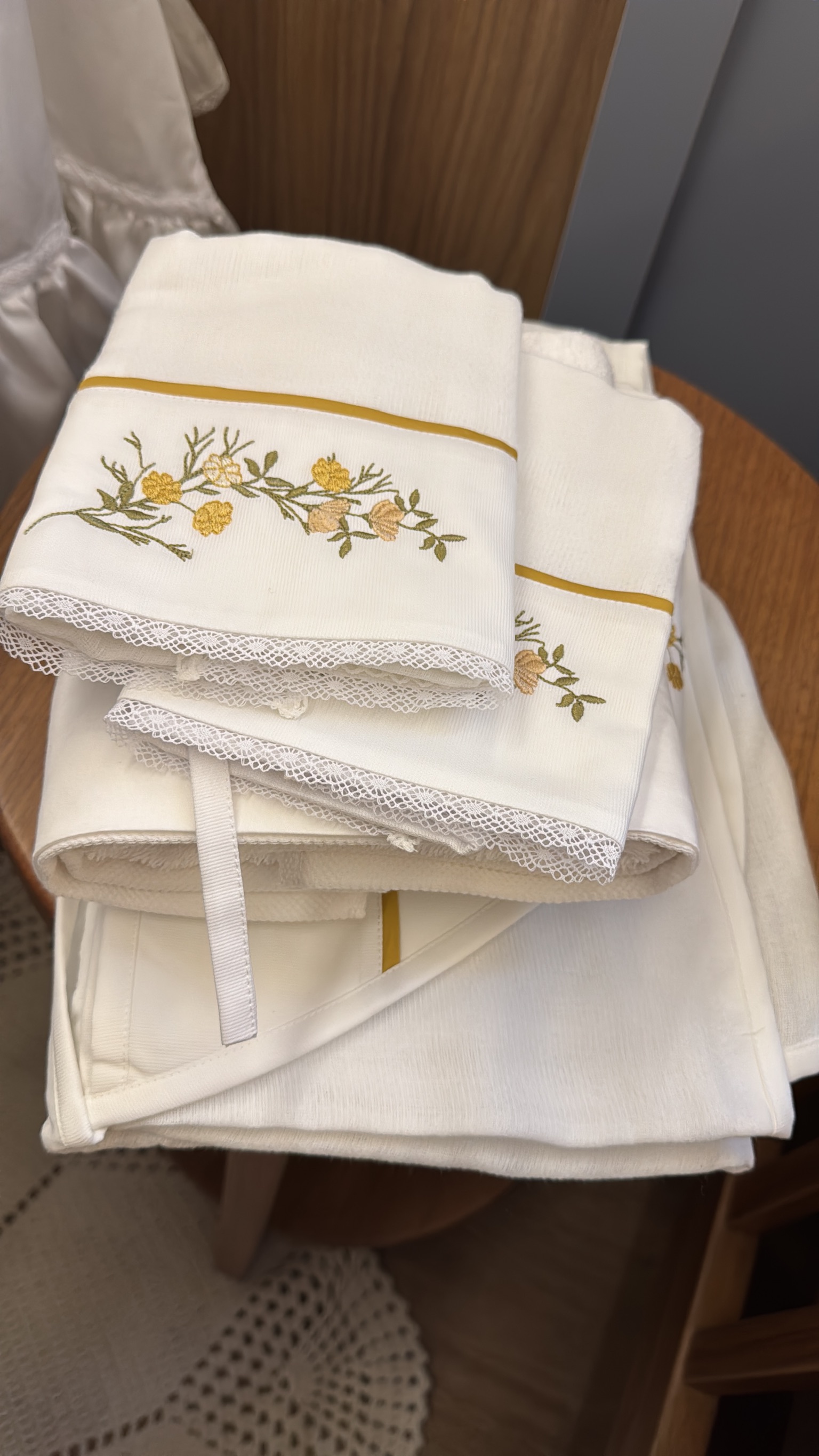 Toalhas e fralda bordadas com flores amarelas e acabamento em renda